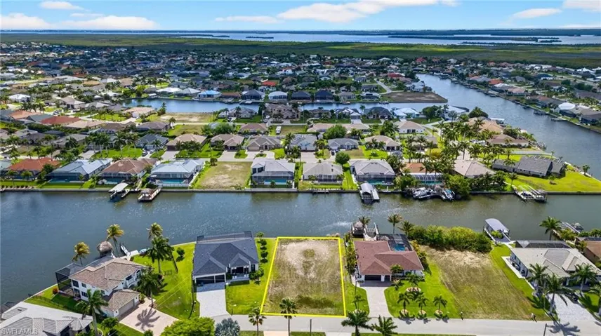 Aerial view of residential area with property parcel outlined and a large body of water