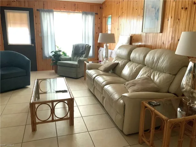 Front entry from driveway w/leather couch, TV & seating