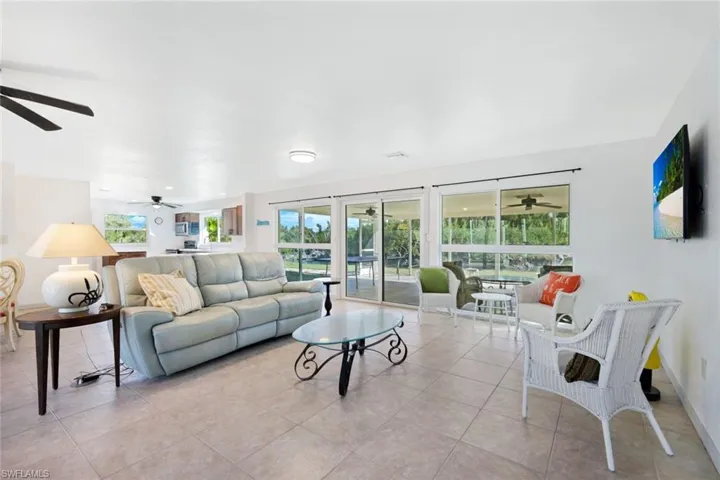Living area featuring a ceiling fan, light tile patterned floors, and a sunroom