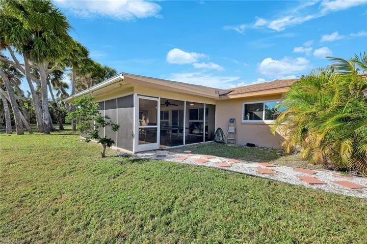 Rear view of house with a yard, a ceiling fan, stucco siding, and a sunroom