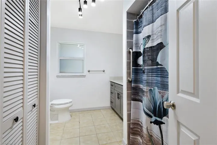 Full bathroom featuring a closet, a shower with shower curtain, vanity, and light tile patterned flooring