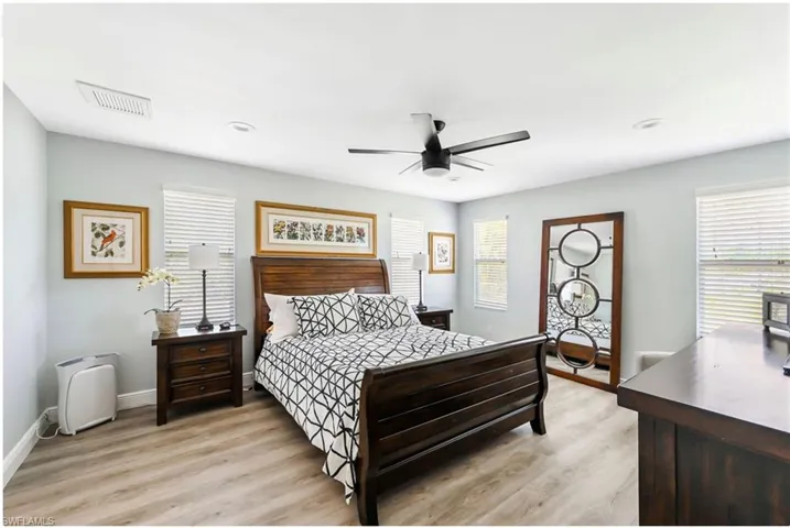 Bedroom with multiple windows, light wood-style flooring, ceiling fan, and baseboards