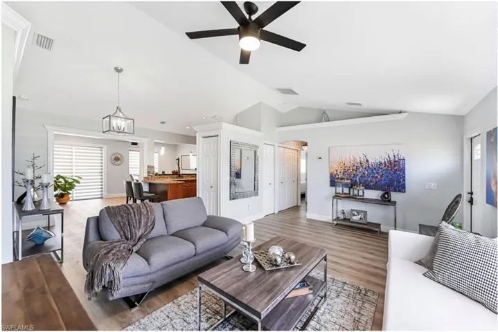 Living room featuring lofted ceiling, wood finished floors, ceiling fan, and baseboards