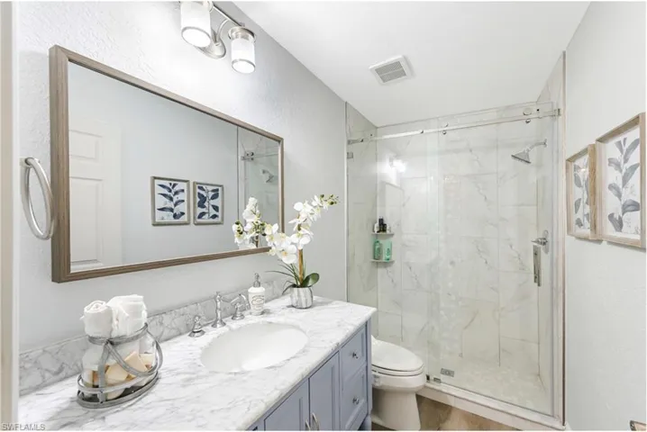 Full bath featuring toilet, a stall shower, and vanity