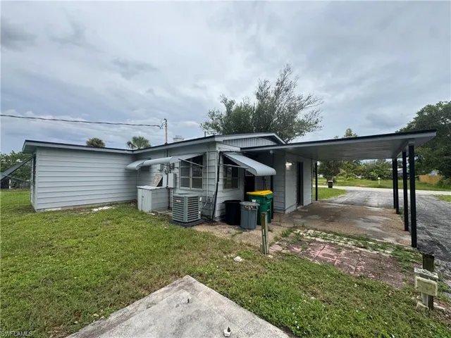View of property exterior featuring a lawn, an attached carport, and driveway