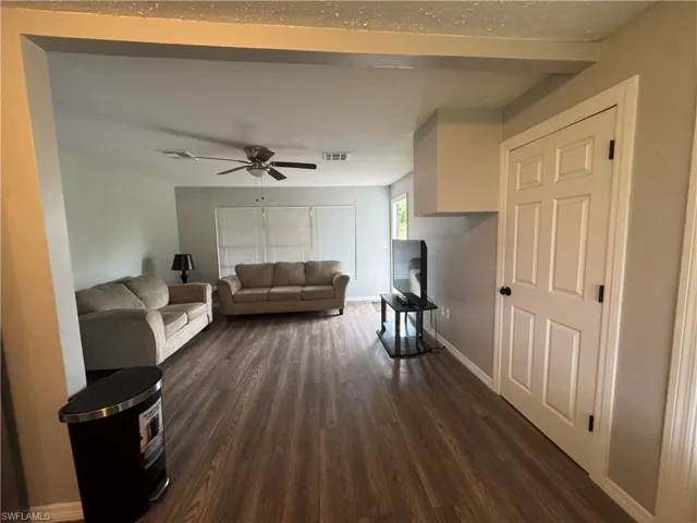 Living area featuring dark wood-style flooring and ceiling fan