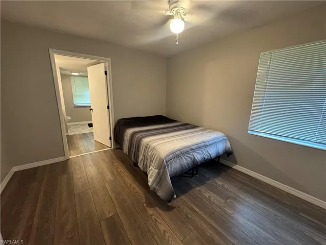 Bedroom with dark wood finished floors, ceiling fan, and ensuite bath