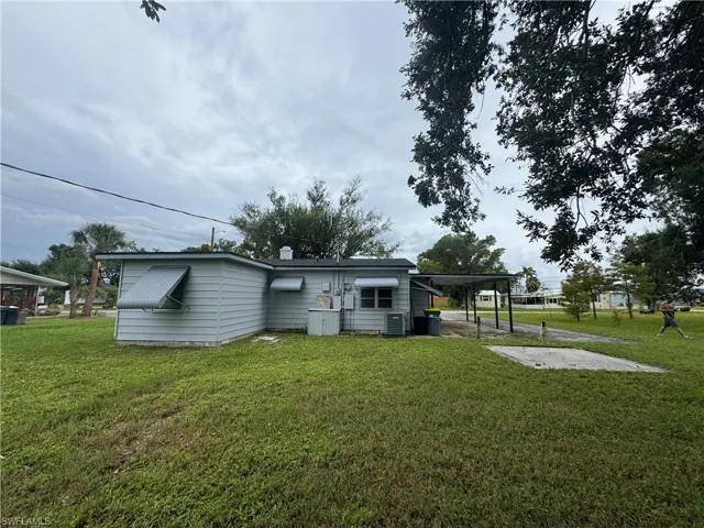 Back of property featuring an attached carport and a lawn
