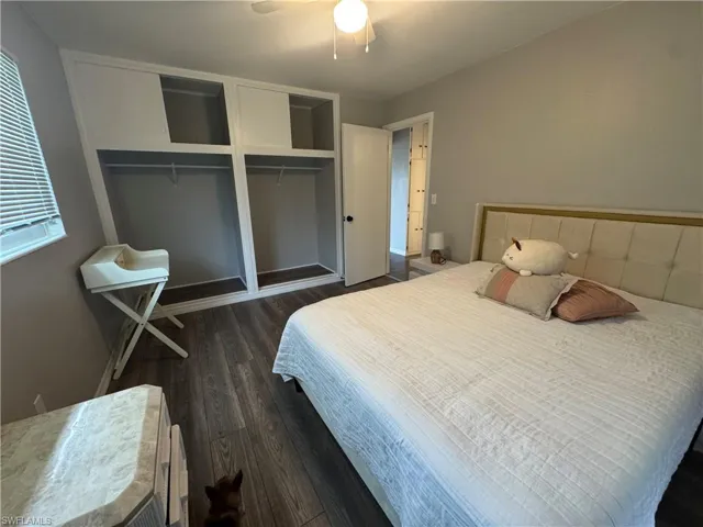 Bedroom featuring dark wood-style flooring, a ceiling fan, and two closets