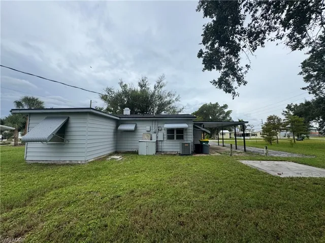 Rear view of house featuring an attached carport and a lawn