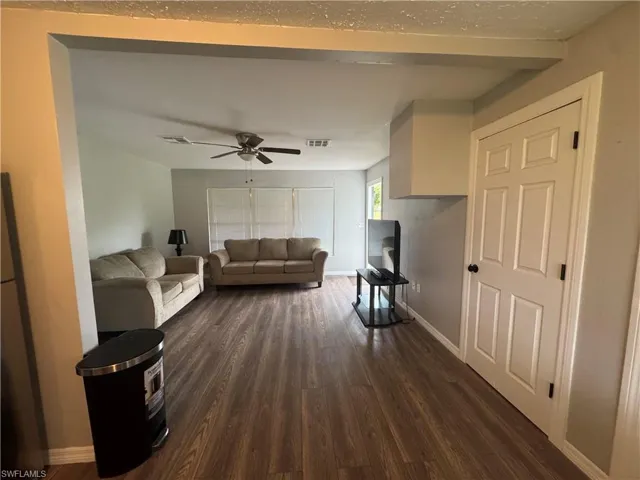 Living room featuring dark wood-type flooring and a ceiling fan