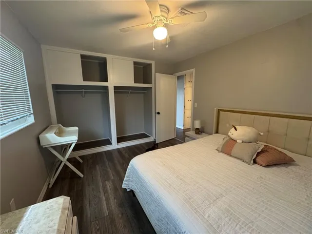 Bedroom with dark wood finished floors, ceiling fan, and two closets