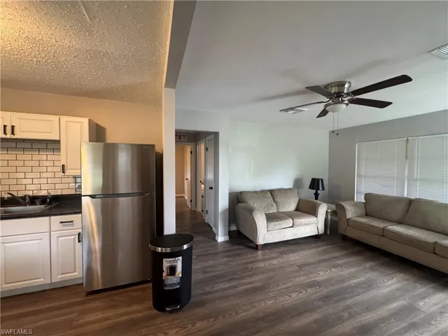 Living area with dark wood-style floors and a ceiling fan