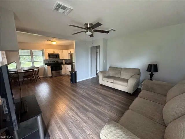 Living area with dark wood-style flooring and a ceiling fan