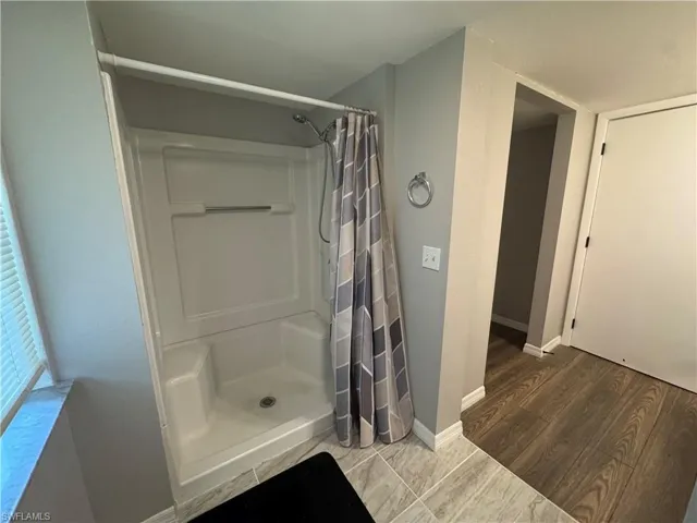 Full bathroom featuring a stall shower and wood finished floors