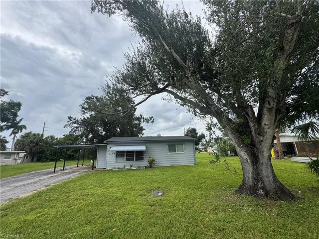View of front of home featuring driveway, a front yard, and an attached carport