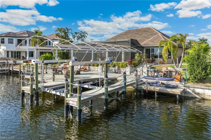 Dock featuring boat lift, a water view, and a lanai