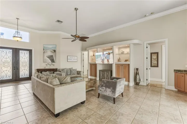 Living room with french doors, light tile patterned flooring, ornamental molding, and a ceiling fan