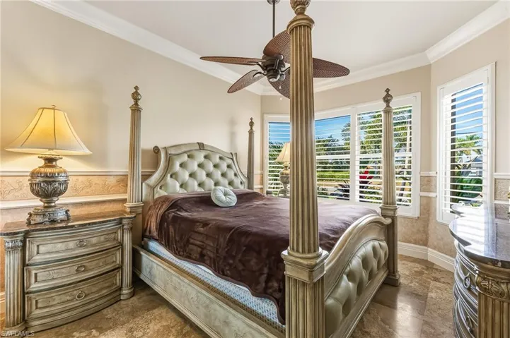 Bedroom featuring ornamental molding, a wainscoted wall, and a ceiling fan