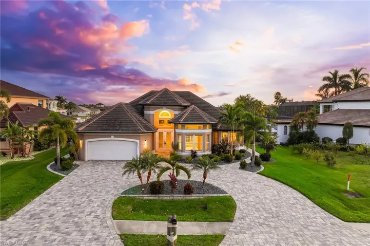 View of front of house featuring a lawn, decorative driveway, an attached garage, and stucco siding
