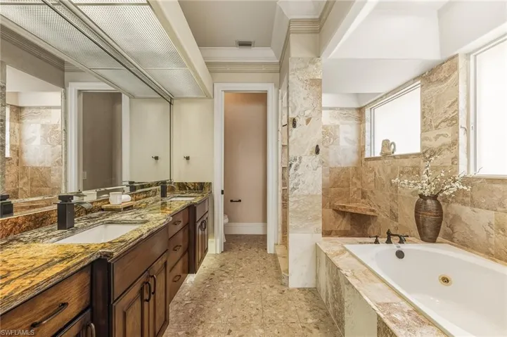 Full bathroom with ornamental molding, double vanity, and a whirlpool tub