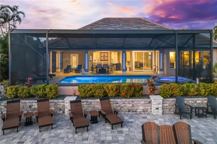 Back of property featuring glass enclosure, a patio, an outdoor pool, and outdoor dining area