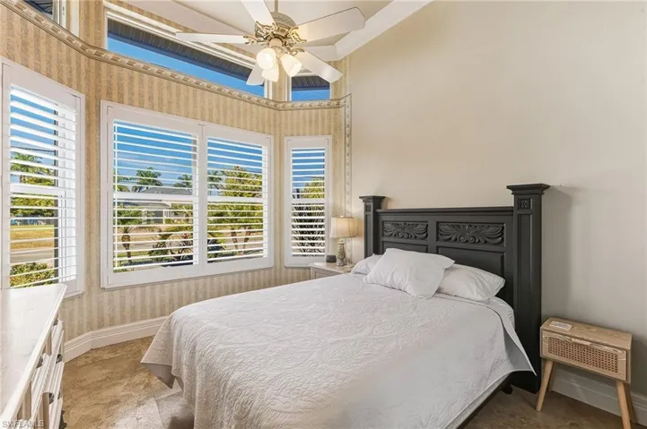 Bedroom with wallpapered walls, a ceiling fan, and ornamental molding