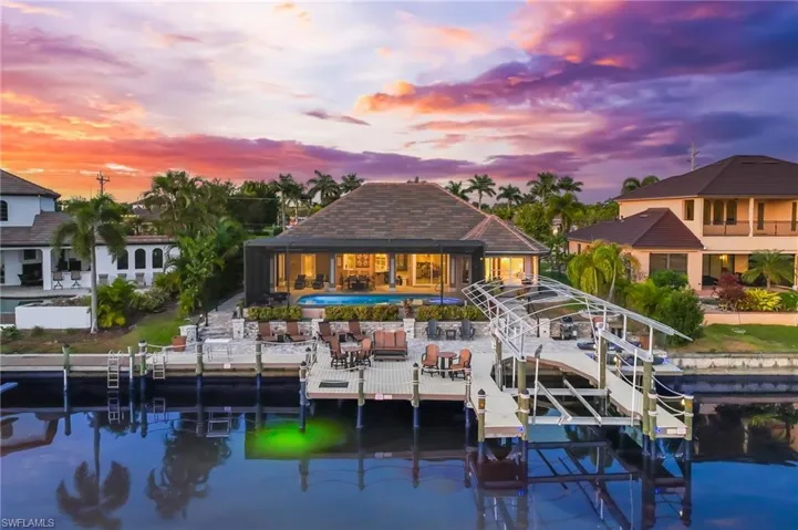 Dock area with boat lift, a patio, an outdoor pool, and a water view