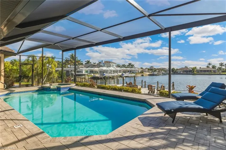 View of swimming pool with a water view, glass enclosure, a patio area, a pool with connected hot tub, and a sunroom