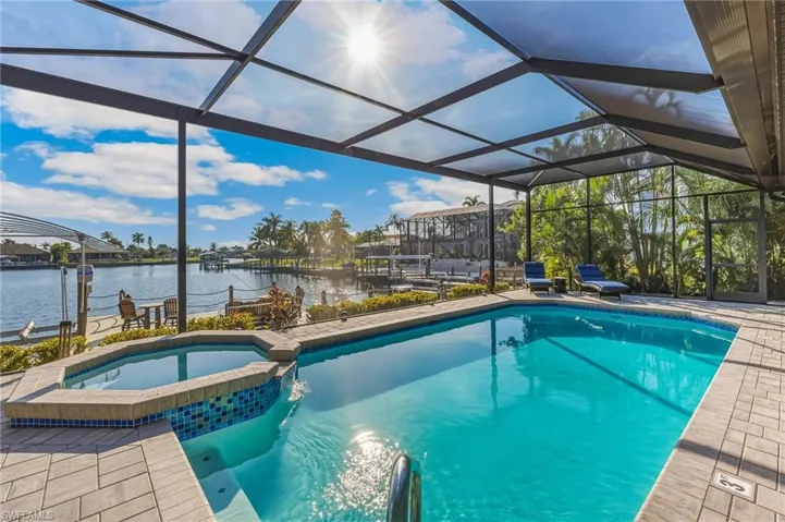 View of swimming pool with a sunroom, a pool with connected hot tub, a water view, and a lanai