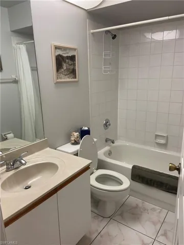 Full bathroom with vanity, shower / bath combination with curtain, marble finish floor, and toilet