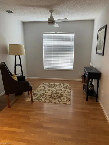 Sitting room with visible vents, light wood-style flooring, a ceiling fan, and a textured ceiling