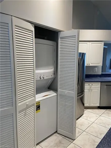 Laundry area featuring marble finish floor, laundry area, and stacked washer and clothes dryer