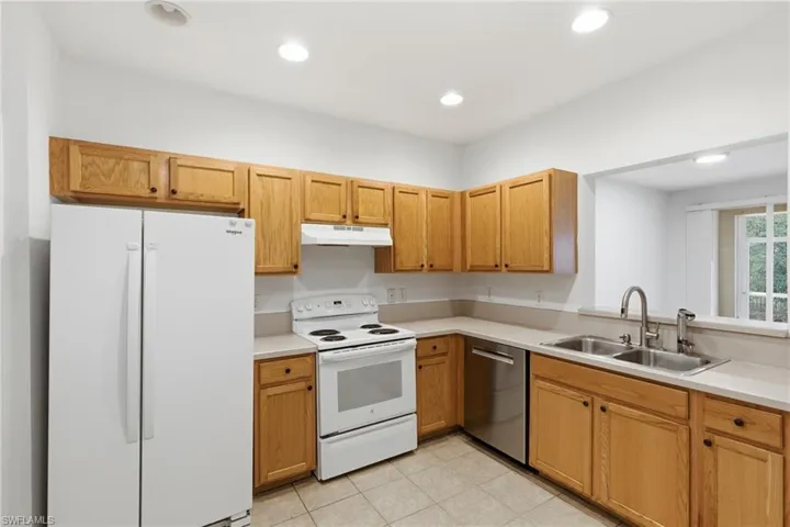 Kitchen with white appliances, light countertops, recessed lighting, and light tile patterned floors