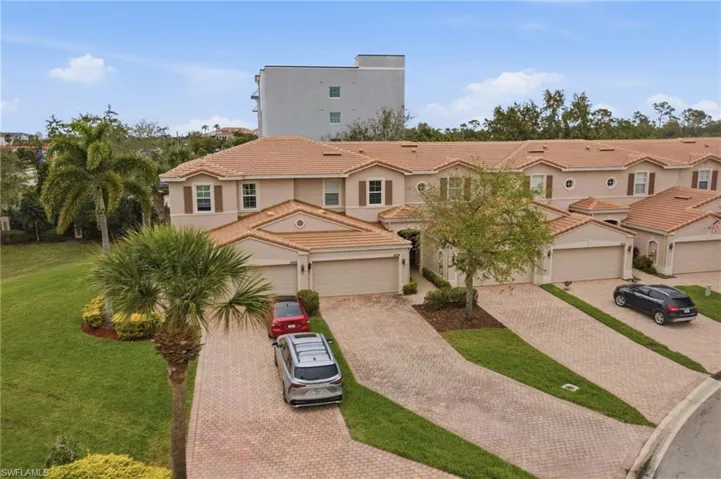 Mediterranean / spanish house with decorative driveway, stucco siding, a residential view, a front lawn, and a tiled roof