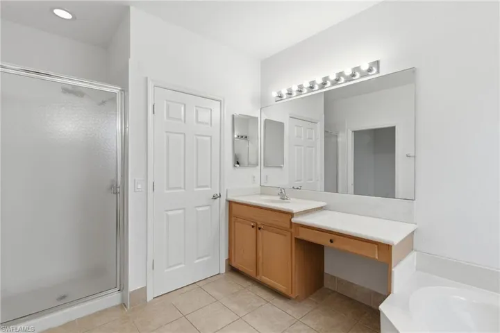 Full bath with vanity, a stall shower, light tile patterned floors, and a bath