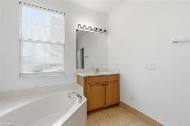 Full bathroom with vanity, light tile patterned flooring, and a garden tub