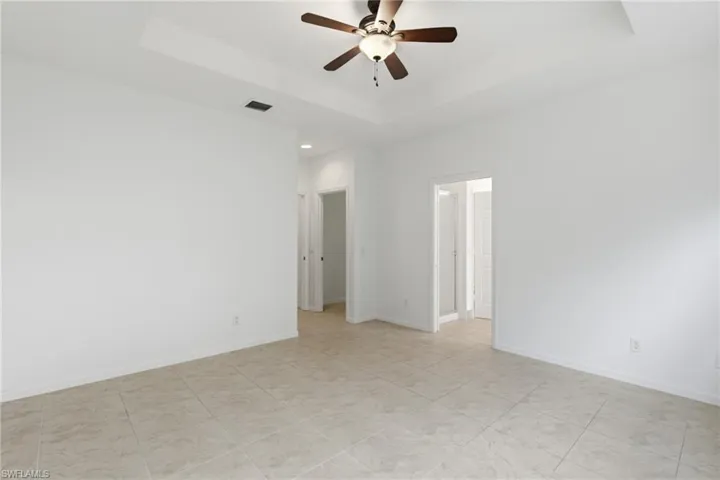 Empty room featuring ceiling fan and a raised ceiling