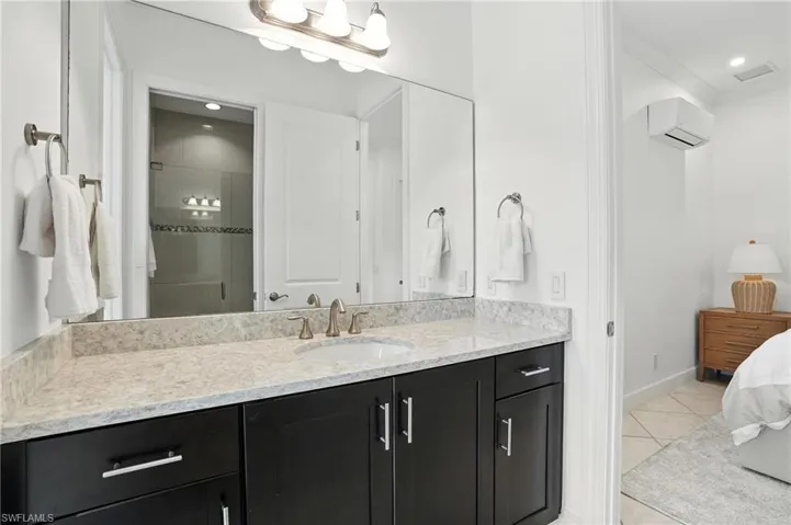 Ensuite bathroom with a wall mounted air conditioner, vanity, ornamental molding, tile patterned floors, and a stall shower