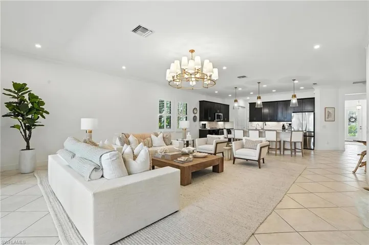 Living area featuring light tile patterned flooring, recessed lighting, a chandelier, plenty of natural light, and ornamental molding