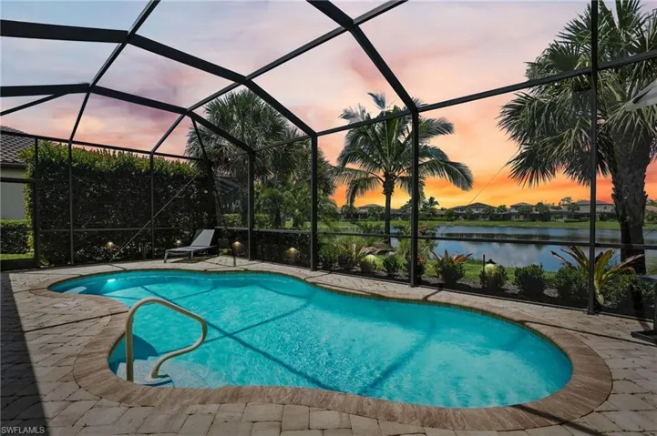 Outdoor pool featuring a patio, a water view, and glass enclosure