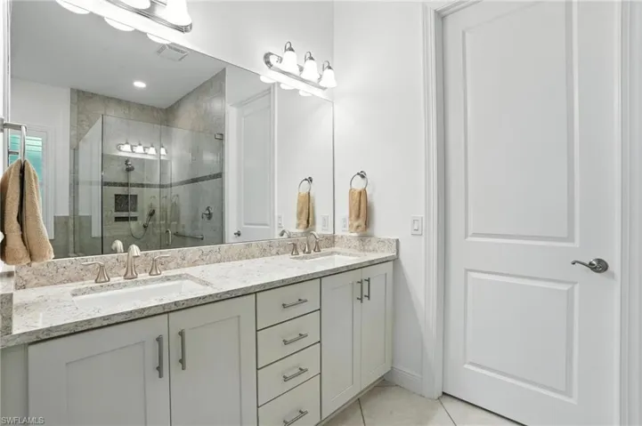 Full bathroom with double vanity, a stall shower, and tile patterned floors
