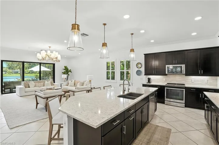 Kitchen featuring stainless steel appliances, light tile patterned flooring, plenty of natural light, decorative backsplash, and crown molding
