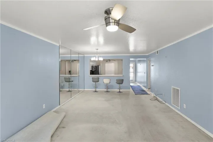 Unfurnished living room with ceiling fan, a textured ceiling, and a chandelier