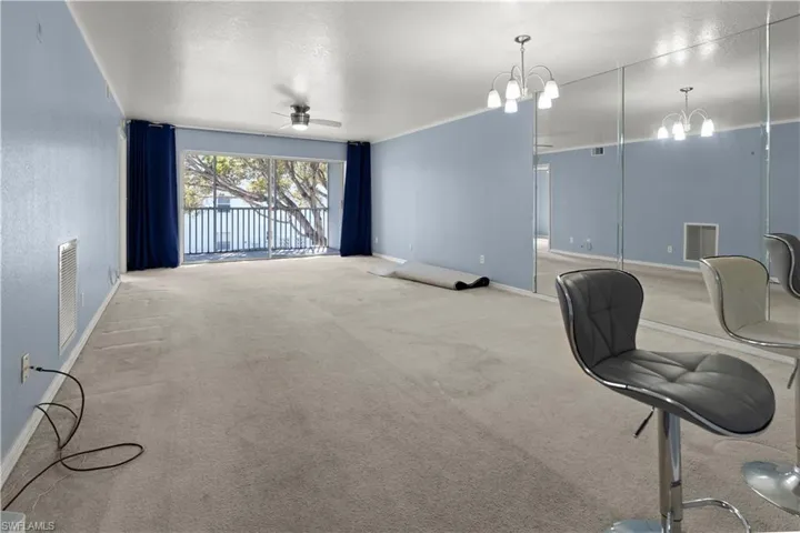 Living room featuring a ceiling fan, carpet, a textured ceiling, and a chandelier
