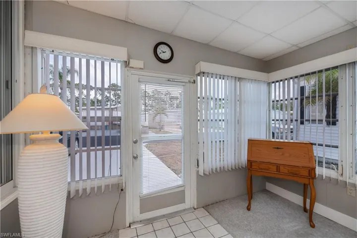 Doorway with plenty of natural light, carpet, baseboards, and a drop ceiling