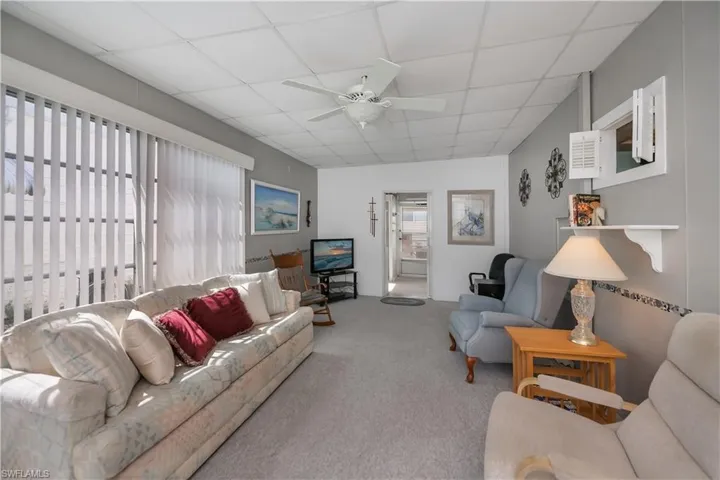 Carpeted living area featuring a ceiling fan and a paneled ceiling