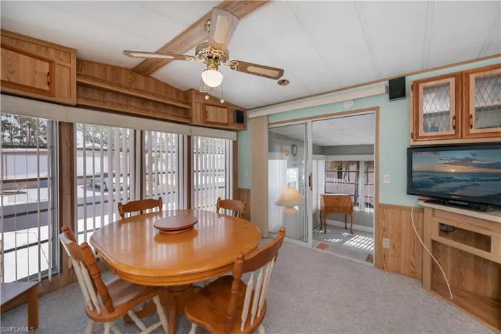 Carpeted dining room with wooden walls, wainscoting, ceiling fan, and plenty of natural light