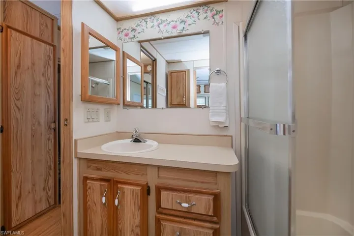 Full bath featuring a shower with shower door and vanity