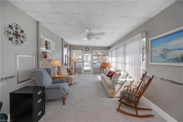 Carpeted living room with baseboards, ceiling fan, and a paneled ceiling